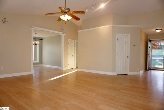 unfurnished room with ceiling fan with notable chandelier, light hardwood / wood-style floors, high vaulted ceiling, and decorative columns