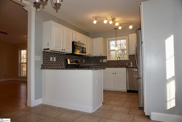 kitchen featuring sink, light tile patterned floors, appliances with stainless steel finishes, tasteful backsplash, and white cabinetry