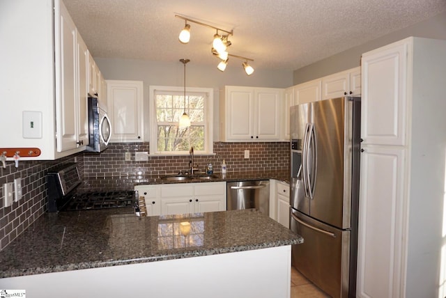 kitchen featuring kitchen peninsula, pendant lighting, stainless steel appliances, and white cabinetry