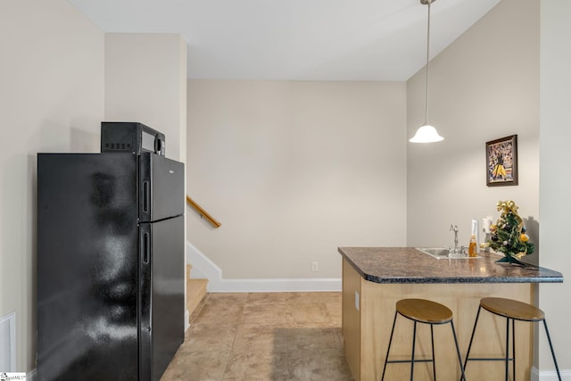 kitchen featuring sink, kitchen peninsula, pendant lighting, a breakfast bar, and black appliances