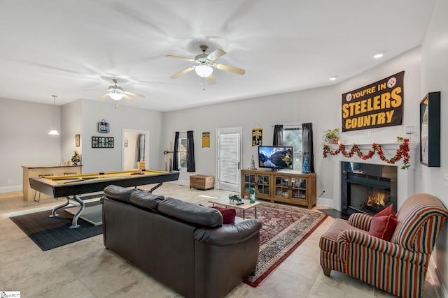 tiled living room with ceiling fan and pool table