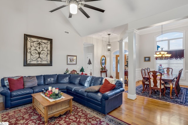 living room with hardwood / wood-style floors, ceiling fan with notable chandelier, vaulted ceiling, and decorative columns