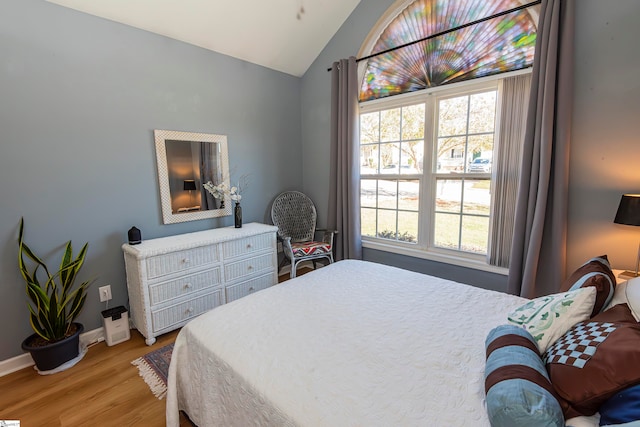 bedroom with light wood-type flooring and vaulted ceiling