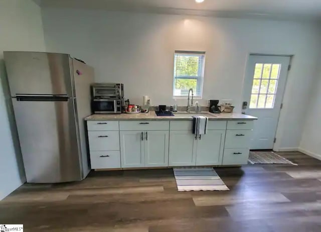 kitchen featuring stainless steel appliances, white cabinetry, a wealth of natural light, and dark hardwood / wood-style floors