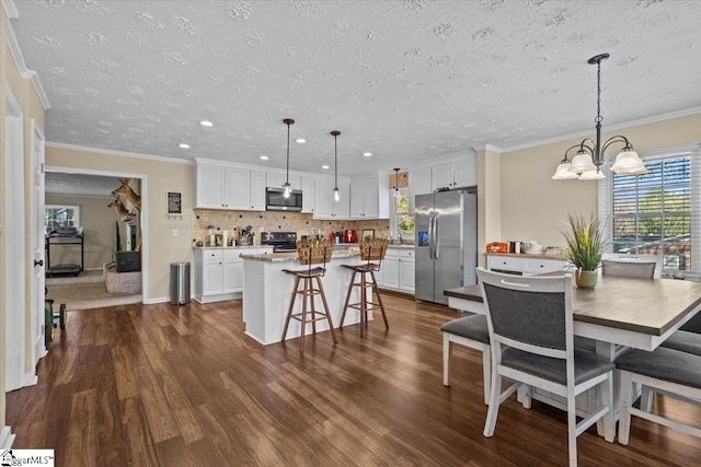 kitchen with pendant lighting, a center island, dark hardwood / wood-style flooring, white cabinetry, and stainless steel appliances