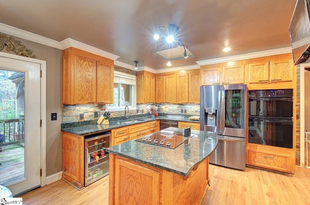 kitchen with black appliances, plenty of natural light, a center island, and light wood-type flooring