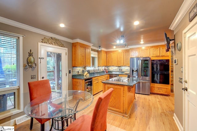 kitchen with sink, tasteful backsplash, stainless steel refrigerator with ice dispenser, double oven, and a kitchen island