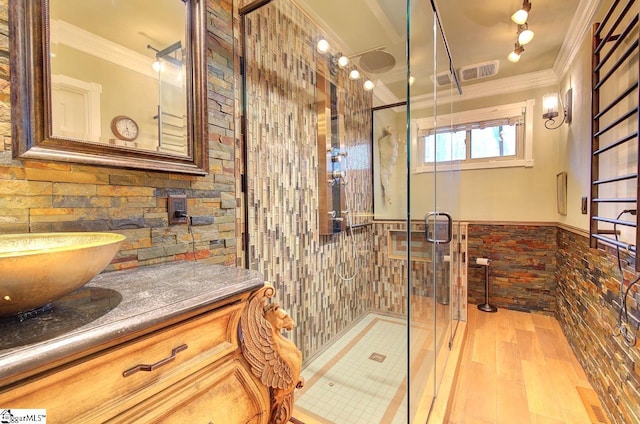 bathroom featuring vanity, walk in shower, crown molding, and tile walls