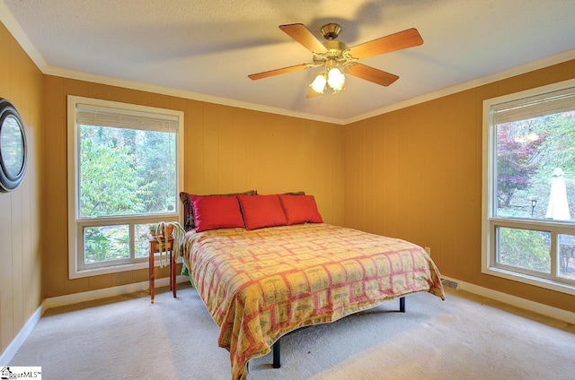 bedroom featuring ceiling fan, light colored carpet, crown molding, and multiple windows