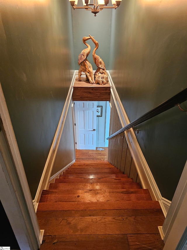 stairs with hardwood / wood-style flooring and an inviting chandelier