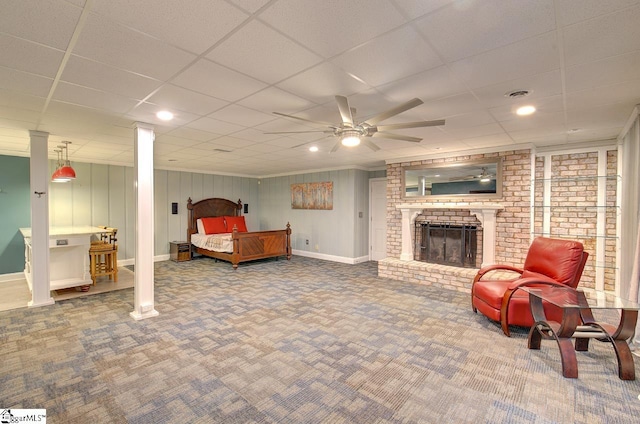 bedroom featuring ceiling fan, a drop ceiling, carpet, and a brick fireplace