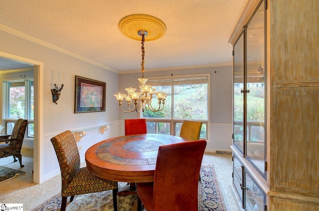 carpeted dining space with ornamental molding, a textured ceiling, and a notable chandelier