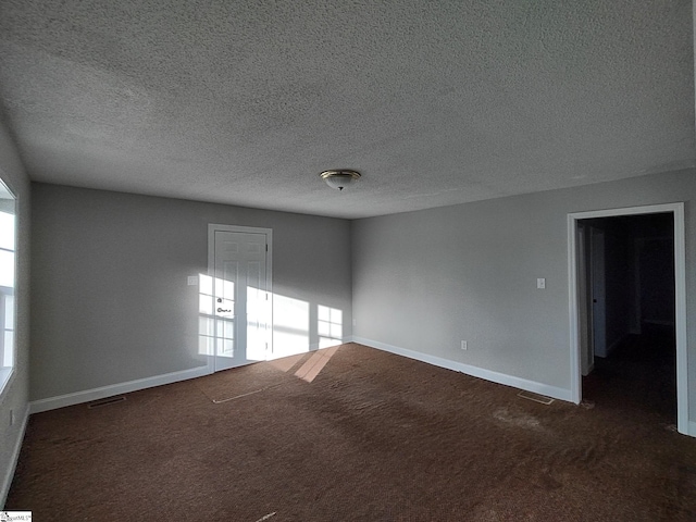 unfurnished room featuring dark colored carpet and a textured ceiling