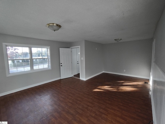 unfurnished room featuring a textured ceiling and dark hardwood / wood-style flooring