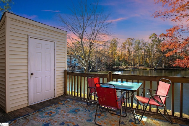 deck at dusk featuring a water view