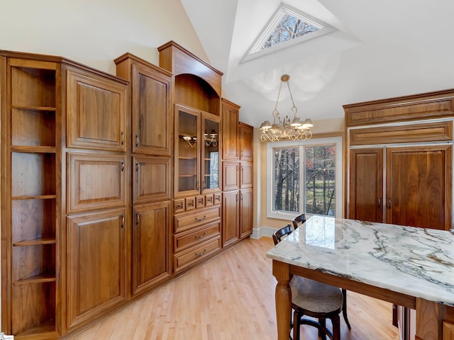 dining room featuring a chandelier, light hardwood / wood-style floors, and vaulted ceiling