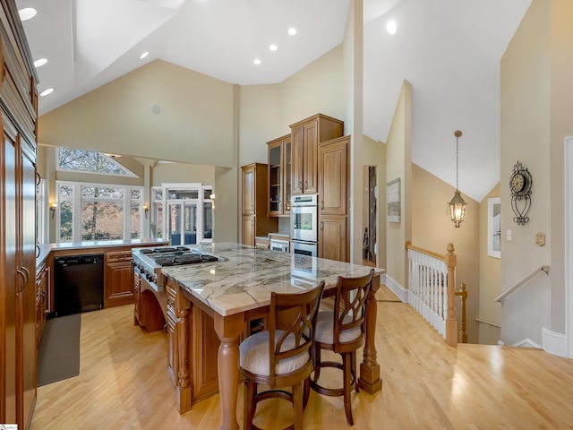 kitchen with a large island, light wood-type flooring, stainless steel appliances, and high vaulted ceiling