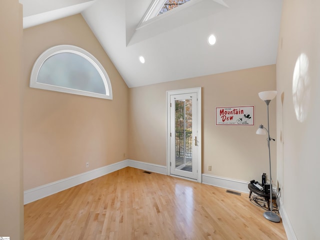 spare room featuring hardwood / wood-style floors and high vaulted ceiling