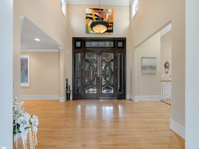 entryway featuring a high ceiling, light hardwood / wood-style floors, crown molding, and a notable chandelier