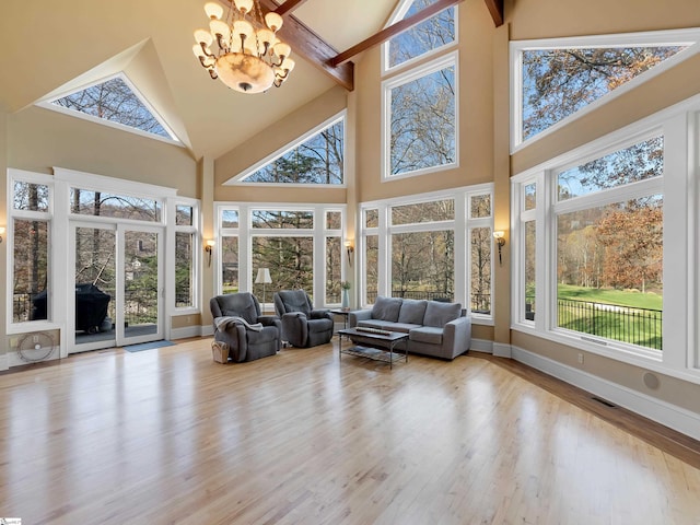 sunroom / solarium featuring a notable chandelier, plenty of natural light, and vaulted ceiling with beams