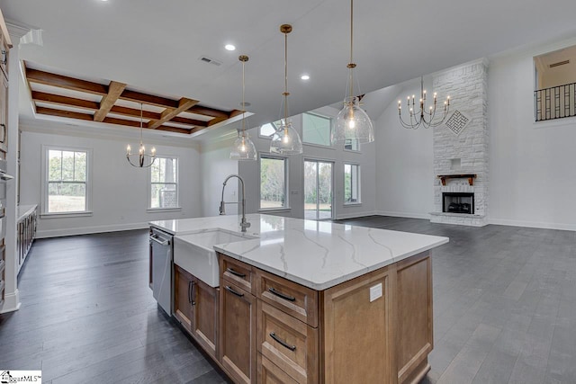 kitchen featuring sink, dark hardwood / wood-style floors, a stone fireplace, hanging light fixtures, and a large island