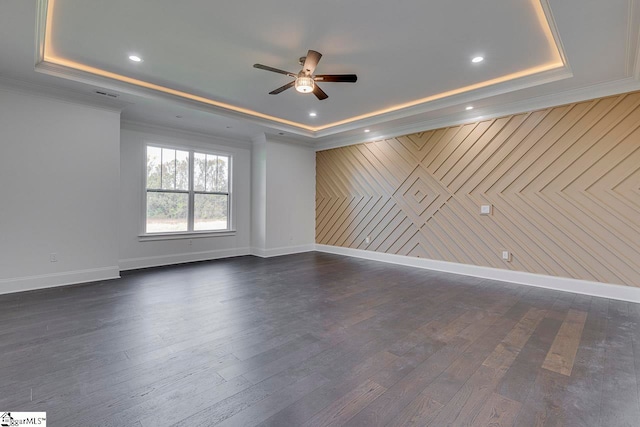 unfurnished room featuring a raised ceiling, wood walls, dark hardwood / wood-style flooring, and ceiling fan