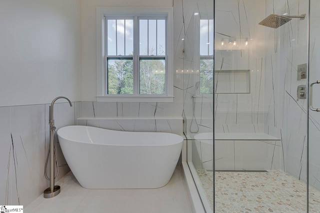 bathroom featuring shower with separate bathtub and tile walls