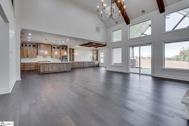 unfurnished living room featuring dark hardwood / wood-style flooring, high vaulted ceiling, an inviting chandelier, and plenty of natural light