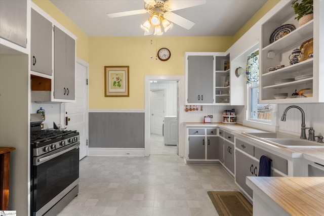 kitchen with backsplash, gray cabinetry, ceiling fan, sink, and stainless steel range with gas stovetop