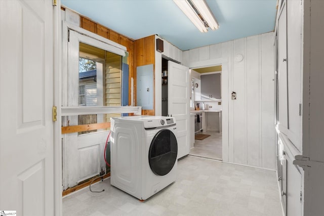 laundry room with washer / dryer, electric panel, and wood walls