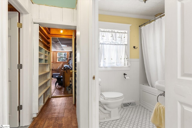 bathroom featuring shower / bath combination with curtain, ornamental molding, wooden walls, hardwood / wood-style flooring, and toilet