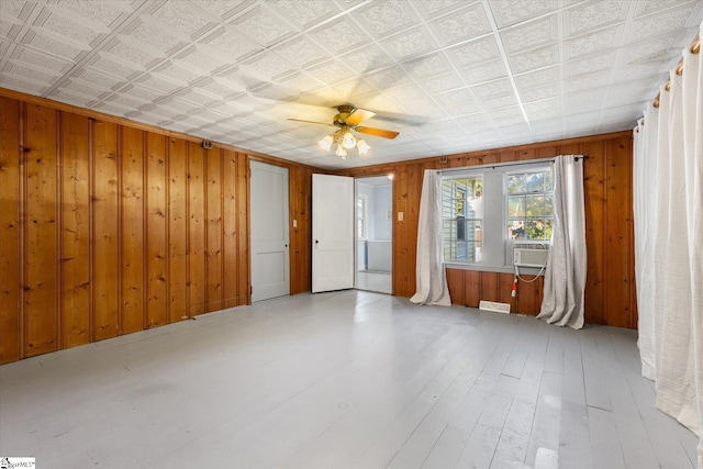 spare room with cooling unit, wood walls, ceiling fan, and light wood-type flooring