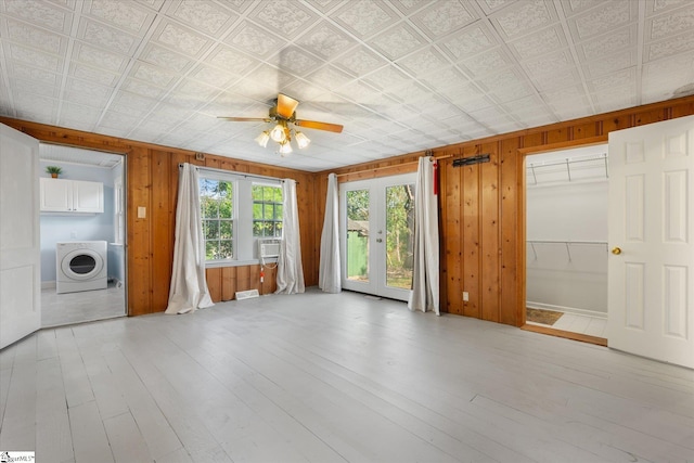 interior space with washer / clothes dryer, wood walls, french doors, and light hardwood / wood-style floors