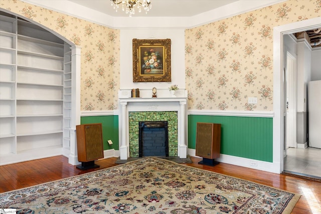 living room with wood-type flooring, built in features, and ornamental molding