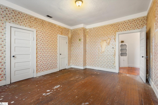 unfurnished bedroom with a textured ceiling and dark hardwood / wood-style floors