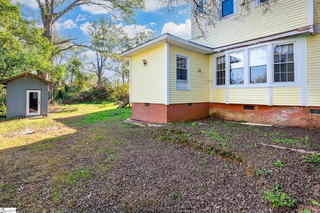 view of side of property with a lawn and a storage unit