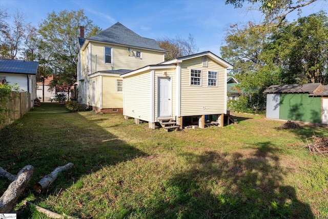 back of house with a yard and a storage shed