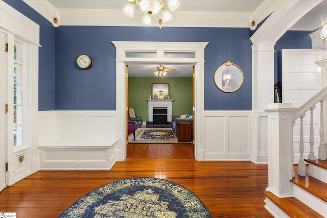 entryway featuring wood-type flooring, crown molding, and an inviting chandelier