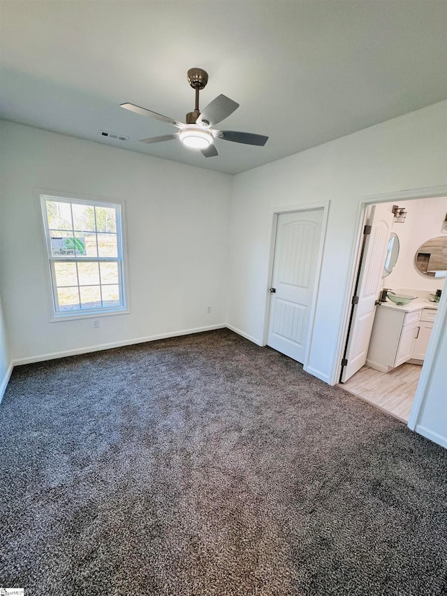 unfurnished bedroom featuring sink, ceiling fan, light colored carpet, and ensuite bathroom