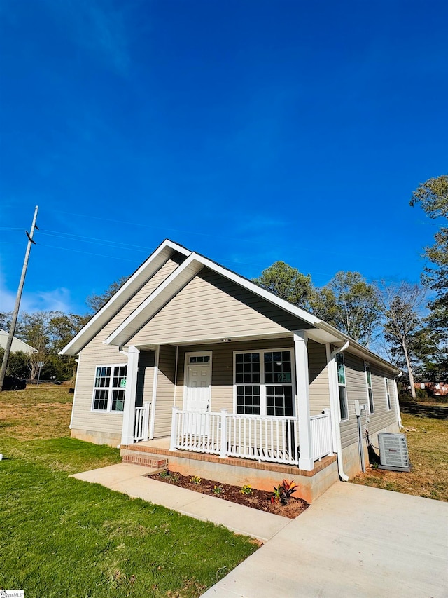 view of front of home with central AC unit, covered porch, and a front yard