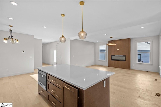 kitchen featuring stainless steel microwave, light hardwood / wood-style flooring, decorative light fixtures, and a notable chandelier