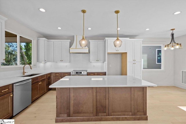 kitchen with stainless steel appliances, white cabinets, custom range hood, and a sink