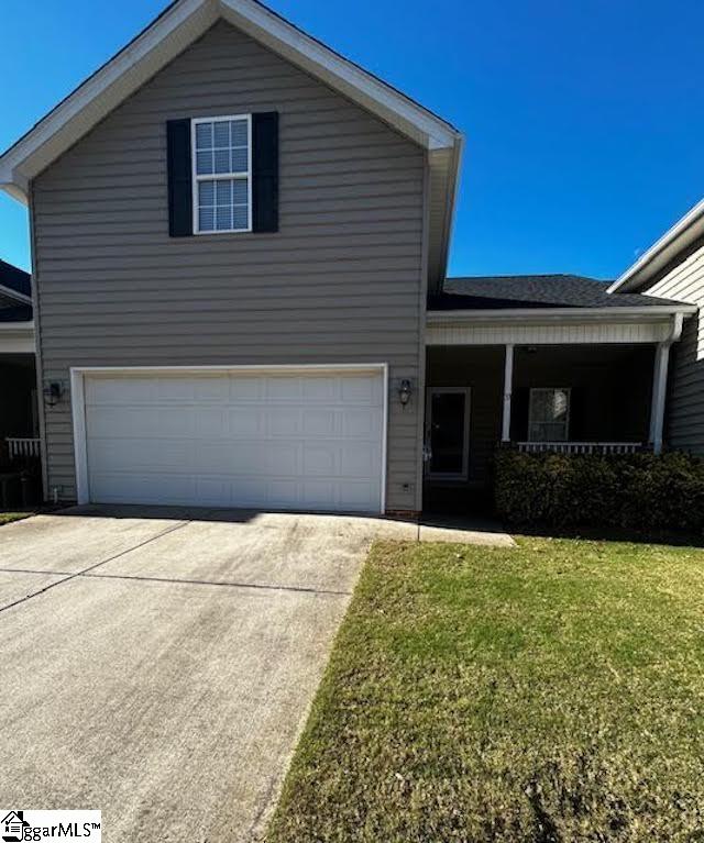 traditional-style house with a garage, concrete driveway, and a front lawn