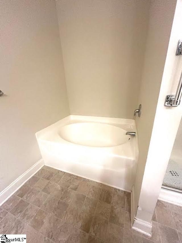 full bath with baseboards and a bath