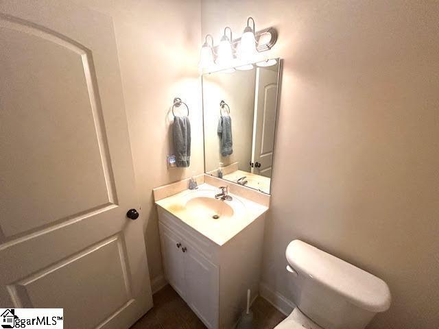 half bath featuring vanity and toilet