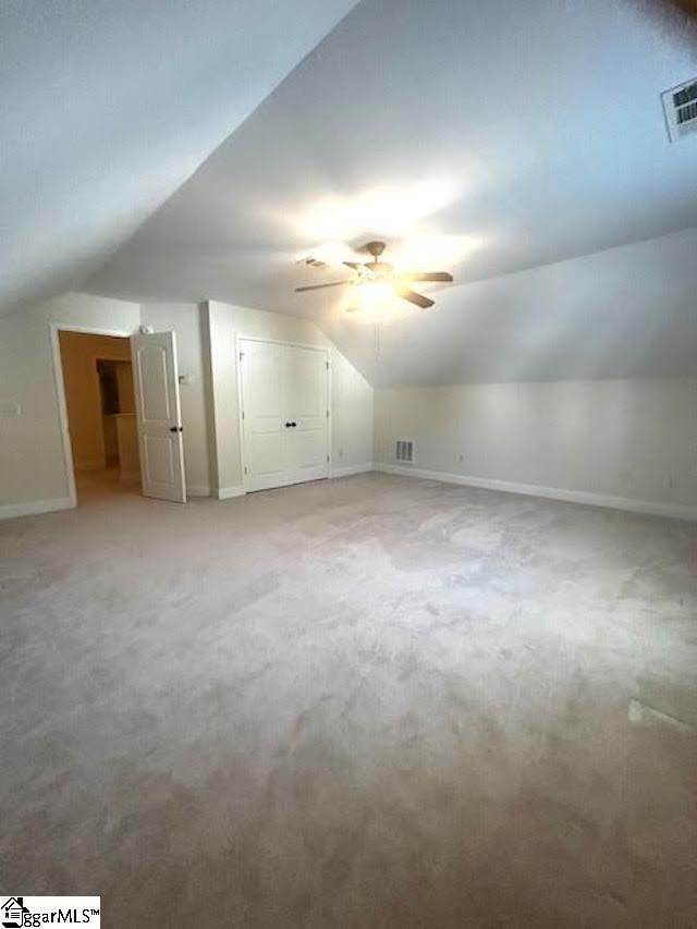 additional living space with lofted ceiling, carpet flooring, visible vents, and baseboards