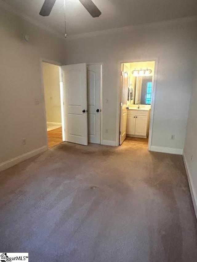 unfurnished bedroom with carpet, connected bathroom, a ceiling fan, and baseboards