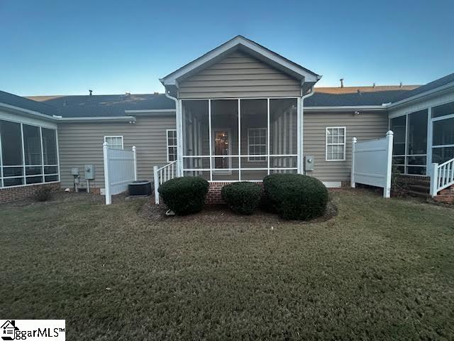 rear view of house with a sunroom, fence, and a lawn