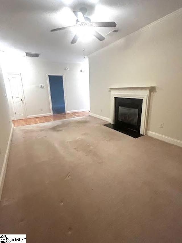 unfurnished living room with baseboards, a fireplace with flush hearth, visible vents, and a ceiling fan