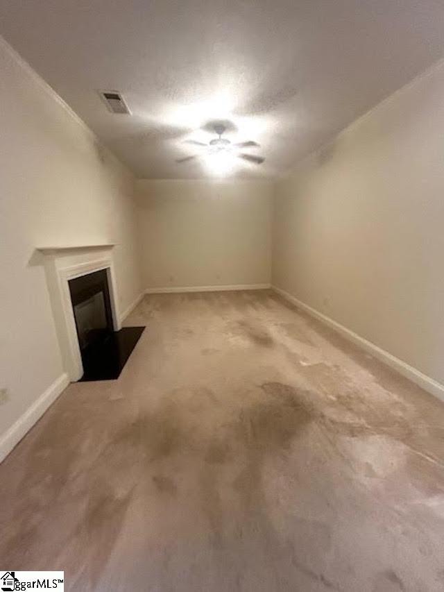 unfurnished living room with a fireplace with flush hearth, baseboards, visible vents, and carpet flooring